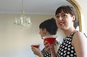 Woman drinking cocktail by mirror