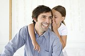 Girl whispering to smiling father