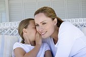 Girl whispering to smiling mother