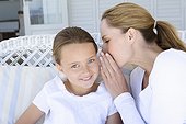 Woman whispering to smiling daughter