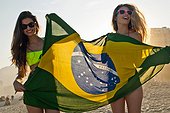 *** IMAGE REMOVED *** Two young women having fun on beach with Brazilian Flag