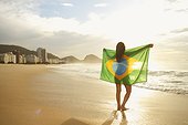 Woman holding Brazilian flag on Copacabana Beach, Rio, Brazil