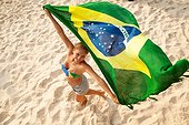 *** IMAGE REMOVED *** Overhead portrait of young woman holding Brazilian flag whilst dancing, Ipanema beach, Rio De Janeiro, Brazil