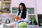 Young woman unpacking groceries and laughing