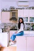 Young woman sitting on kitchen counter
