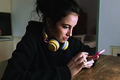 Young woman with headphones, looking at her phone