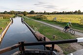 Man cycling beside canal lock