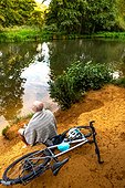 Swimmer sitting beside river with bicycle