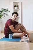 Man at home with exercise mat and laptop