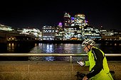 Cyclist with phone in city at night, London, UK