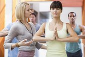 Woman practicing yoga assisted by instructor