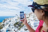 Teenage girl (16-17) photographing town, Santorini, Cyclades, Greece