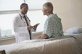Patient sitting on hospital bed and talking to doctor