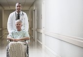 View of doctor with patient on wheelchair in hospital corridor