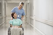 View of doctor with patient on wheelchair in hospital corridor