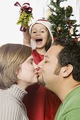 Daughter Holding Mistletoe Over Kissing Parents