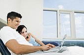 Couple Using Laptop in Bed
