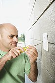 Man with Screwdriver at Electrical Outlet