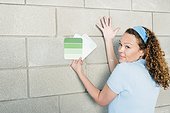 Woman Holding up Paint Samples Against a Wall