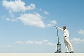 Man standing out doors, vacuuming clouds, side view