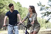 Young couple looking at each other while resting on bicycles