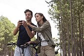Young couple using smart phone in pine forest