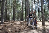 Young couple cycling in pine forest