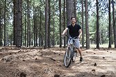 Young man cycling in pine forest