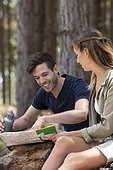 Young couple reading map while sitting in the forest