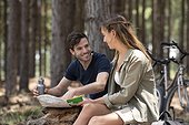 Smiling young couple reading map while sitting in the forest