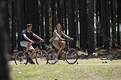 Young couple cycling on dirt track in forest