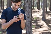 Young man using phone in forest