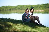 Boy and teenage girl sitting outdoors