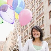 Asian woman holding bunch of balloons