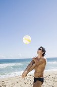 Hispanic man playing volleyball at beach