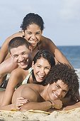 Multi-ethnic friends laying in pile on beach
