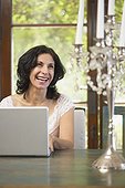 Confident Middle Eastern woman typing on laptop in dining room