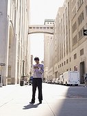 Indian man text messaging on city sidewalk