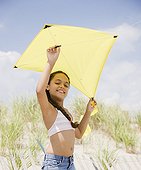 Hispanic girl flying kite on beach