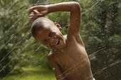 African American boy playing in sprinkler