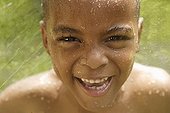Close up of African American boy in sprinkler