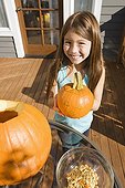 Mixed race young girl holding Halloween pumpkin