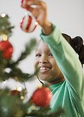 African American girl putting ornament on Christmas tree