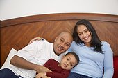 Mixed race boy lounging in bed with parents