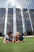 Caucasian couple laying together in grass near building