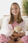 Smiling girl (12-13) holding teddy bear