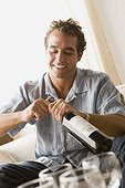 Smiling man opening bottle of wine
