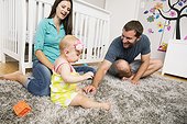 Mid adult couple playing with baby daughter on nursery rug