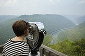 Mid adult woman looking through coin operated binoculars,  rear view, New River Gorge National River, Fayetteville, West Virginia, USA