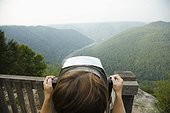 Mid adult woman looking through coin operated binoculars,  rear view, New River Gorge National River, Fayetteville, West Virginia, USA